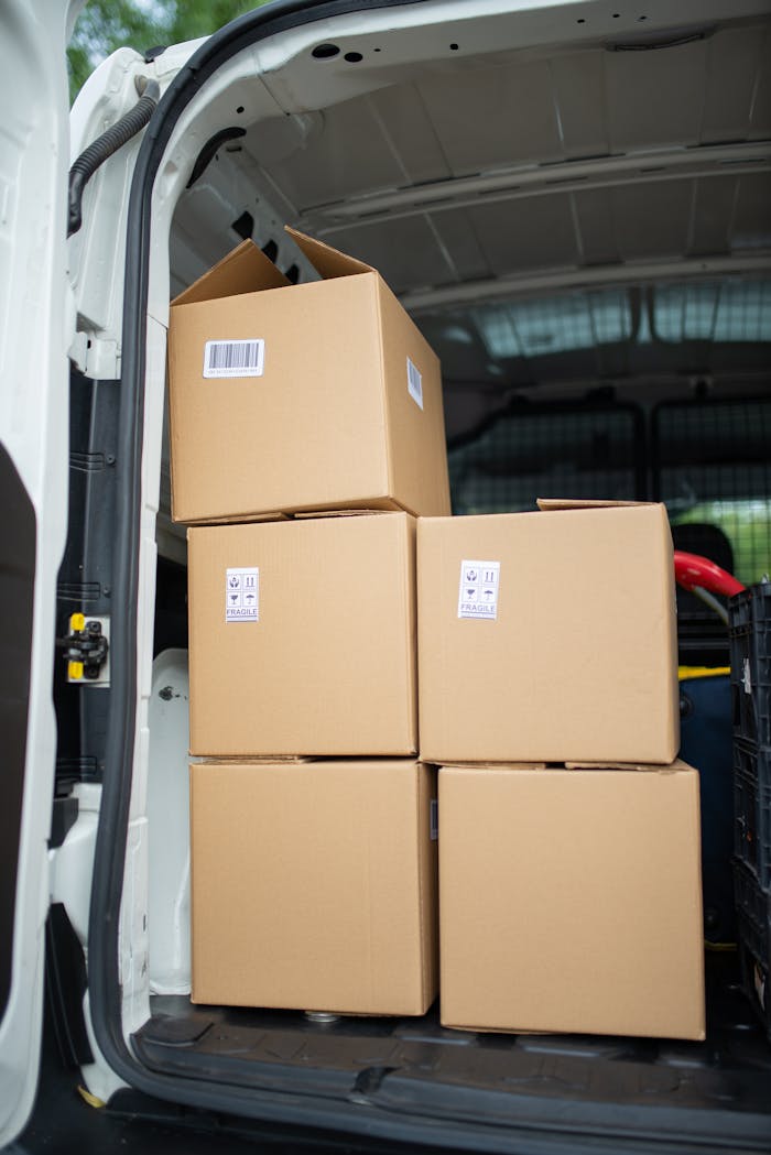 Stacked cardboard boxes inside an open delivery van, ready for shipment.